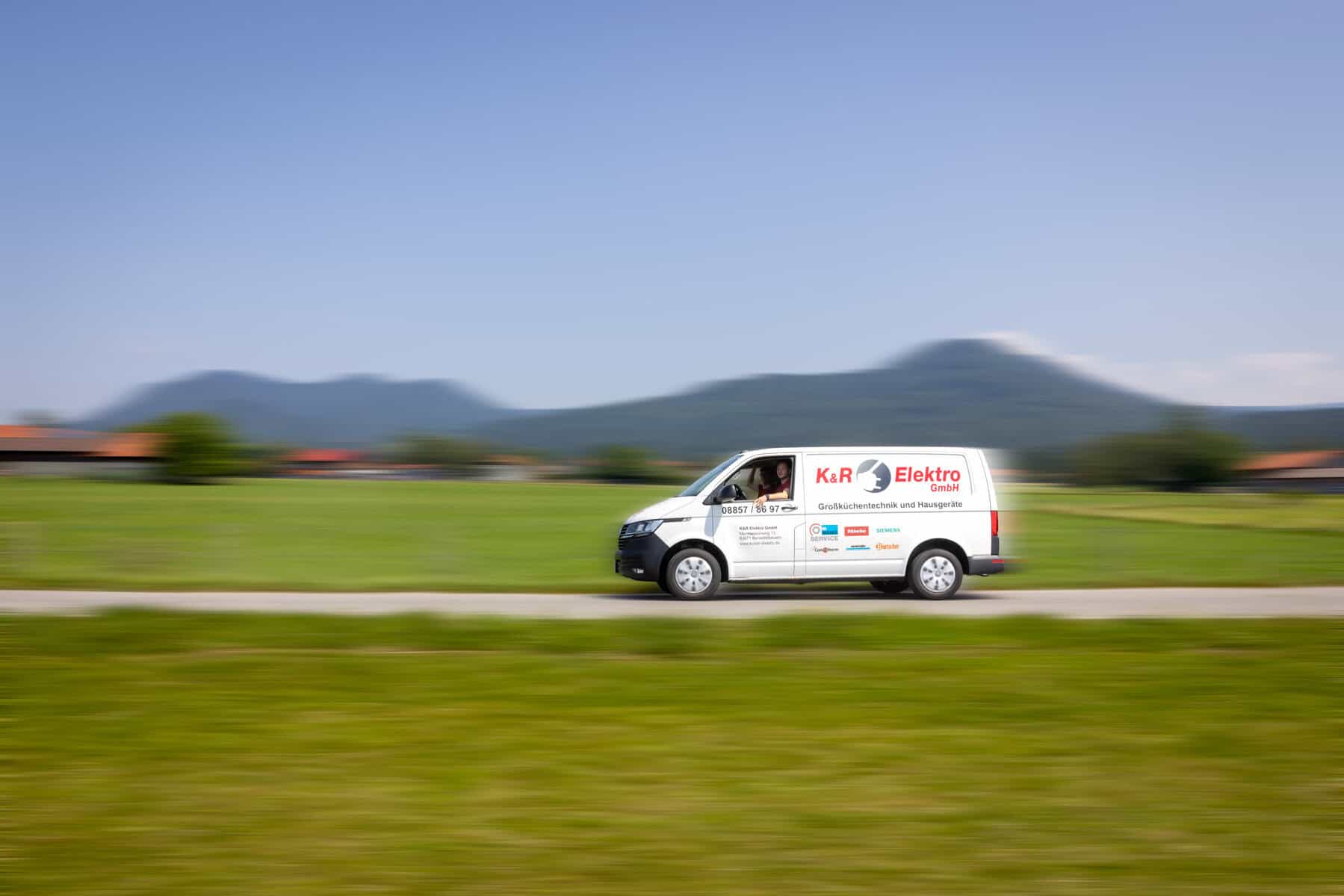 Lieferwagen von K&R Elektro GmbH auf Landstraße unterwegs.