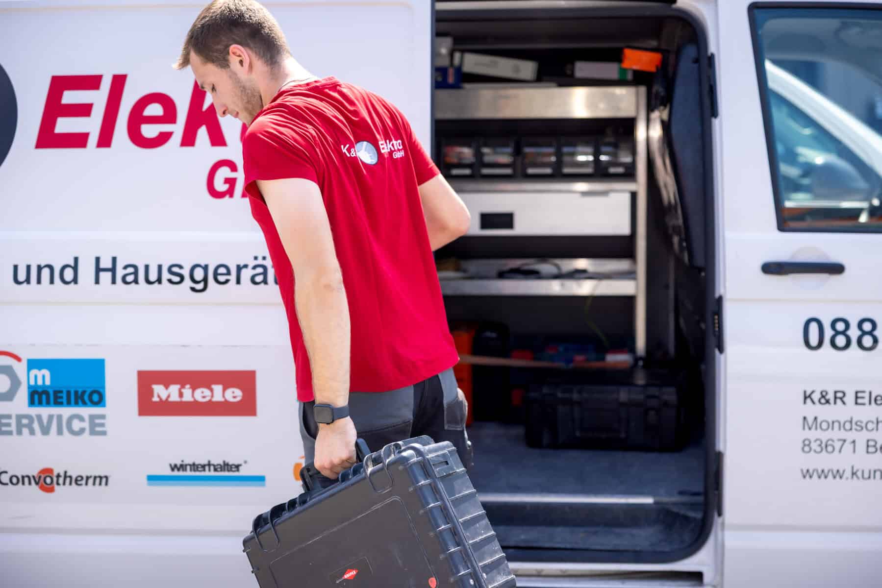 Elektriker lädt Werkzeugkoffer in Firmenfahrzeug bei K&R Elektro GmbH.